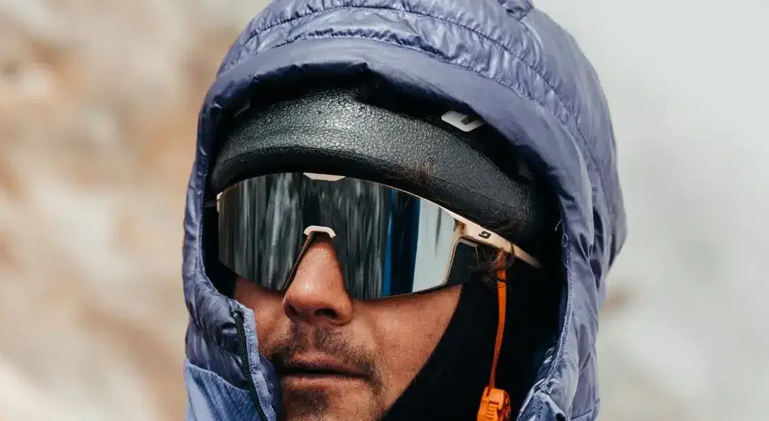 Alpiniste portant une capuche bleue et des lunettes de soleil Julbo à verres miroirs réfléchissants.