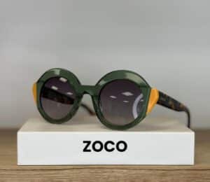 Lunettes ZOCO rondes vertes, touches jaunes, branches écailles sur boîte blanche.